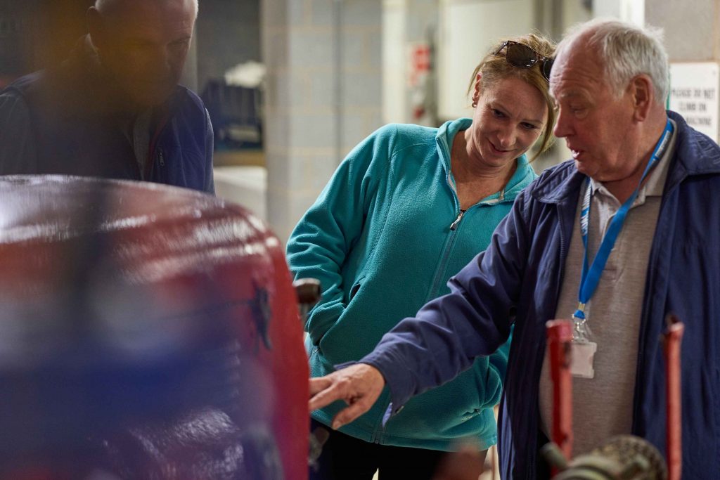 Volunteer explains machinery to a visitor