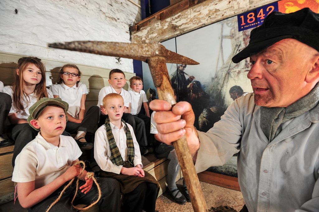 School children watching a Living History Intepretator talk about life in the Victorian Era as a Miner