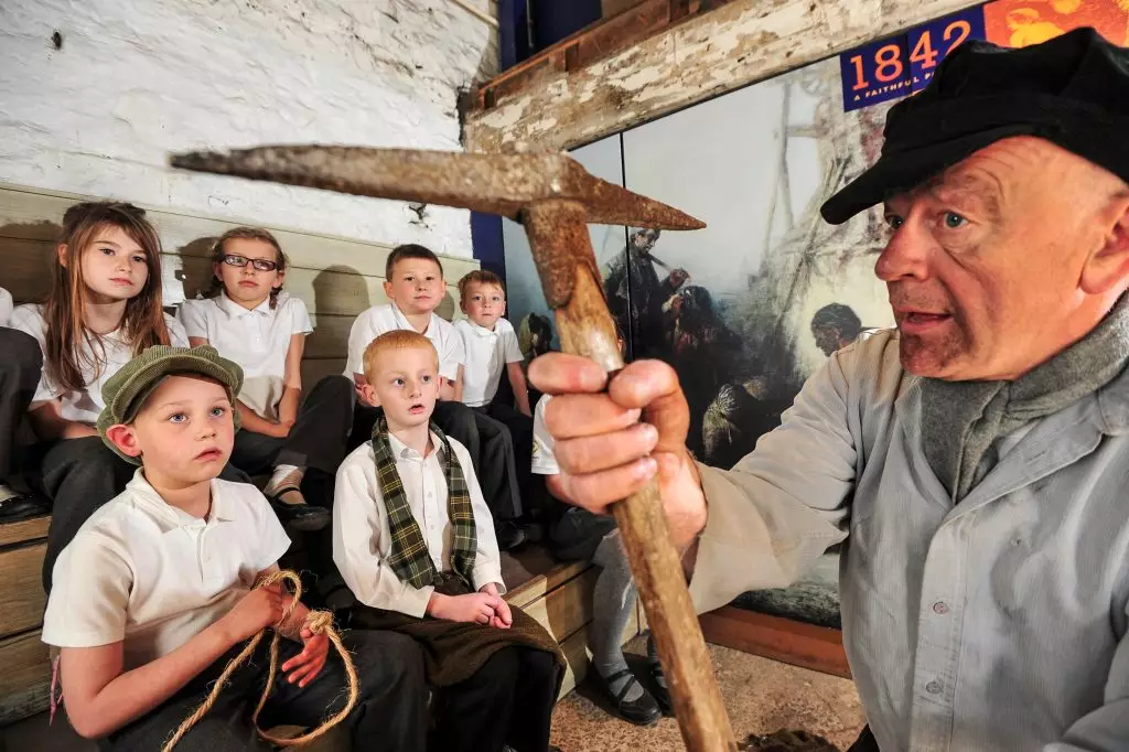 School children watching a Living History Intepretator talk about life in the Victorian Era as a Miner