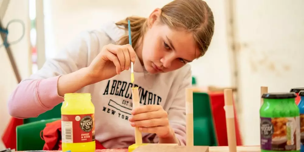 Girl painting a game she has made in a Caphouse Creators workshop.