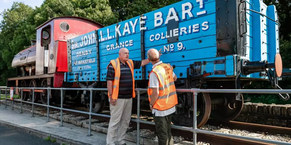 Two volunteers talking about blue machinery