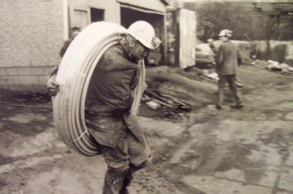 Miner Carrying a Coil of Pipe Miner Carrying a Coil of Pipe