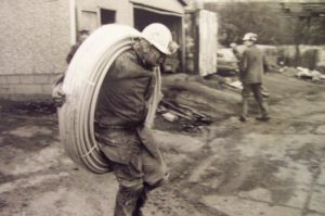 Miner Carrying a Coil of Pipe