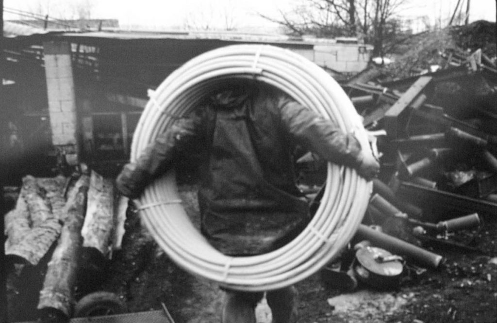 Miner Carrying a Coil of Pipe