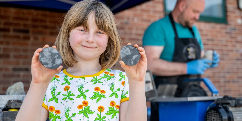 A child smiling holding fossils that have been cut open at Geology Rocks
