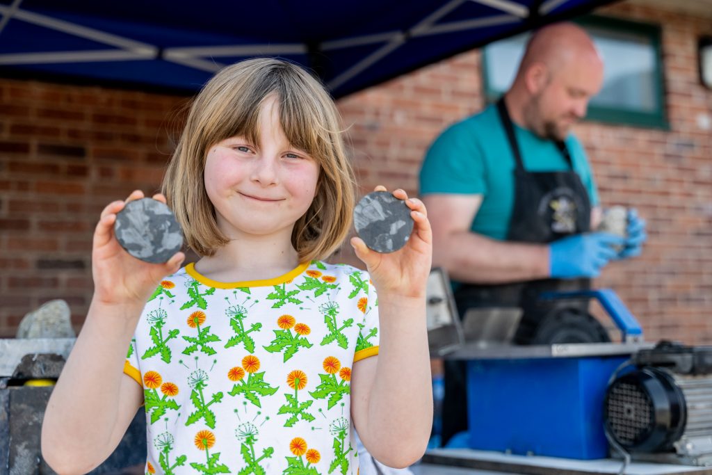 A child smiling holding fossils that have been cut open at Geology Rocks