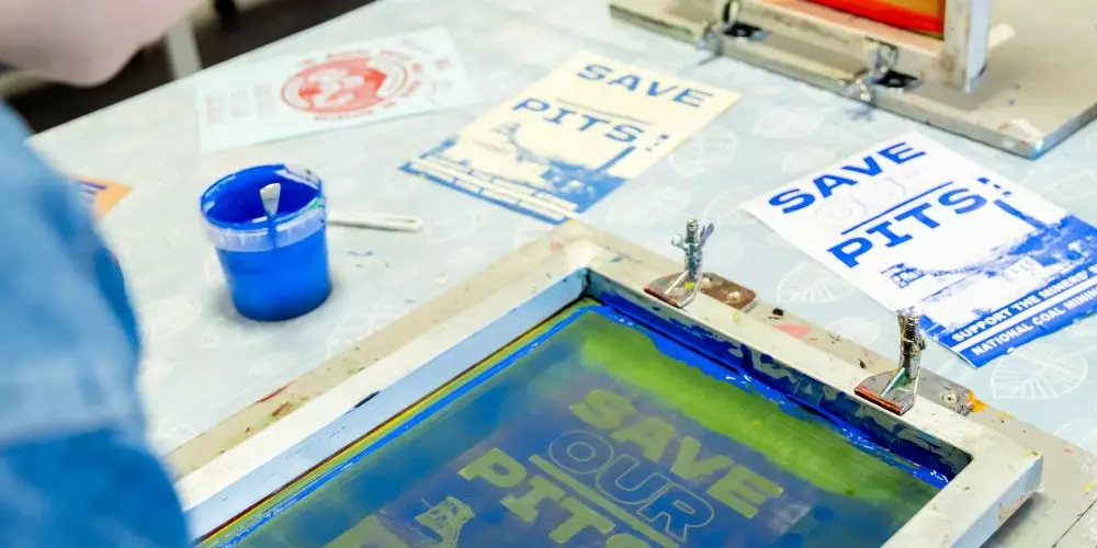 A woman screen printing a design onto paper