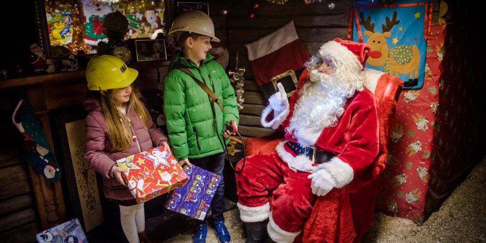 Santa Underground, two children and Santa seated.