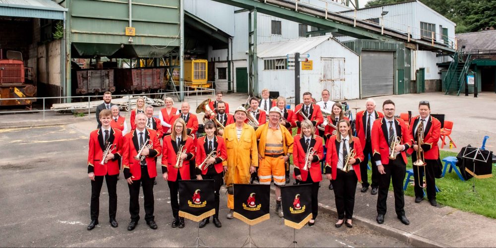 Hade Edge stood in Caphouse Pit Yard smiling with two miners