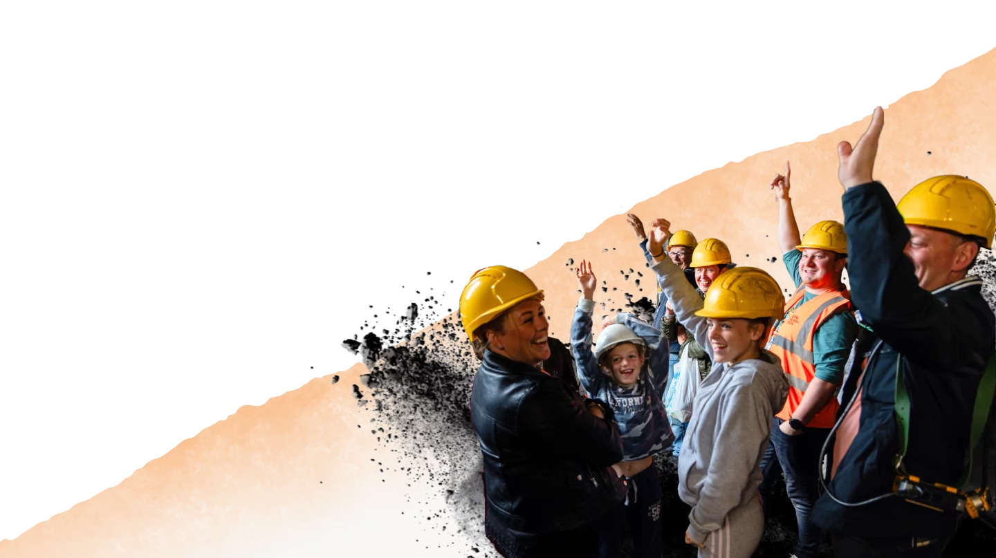 Visitors on a Screens Tour wearing hard hats and raising their arms and laughing