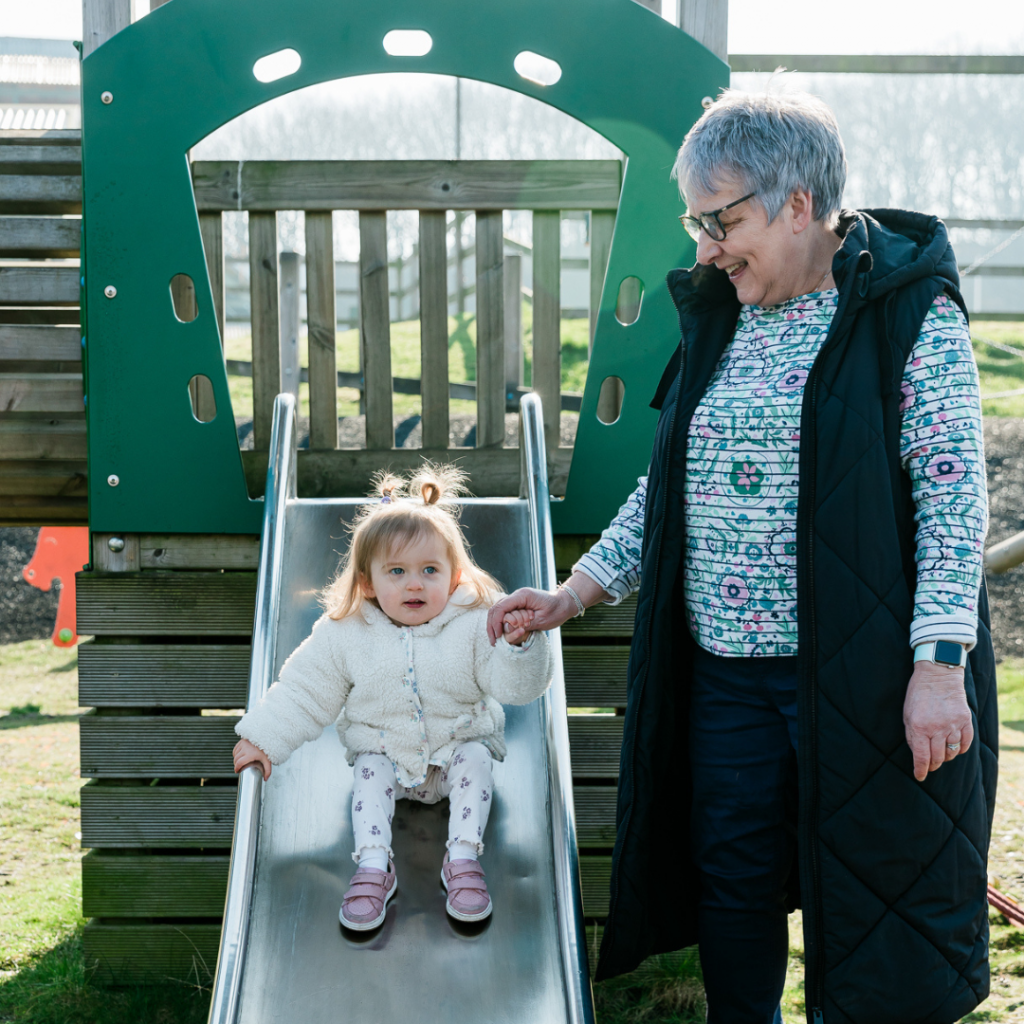 A young girl and her grandma playing on the slide