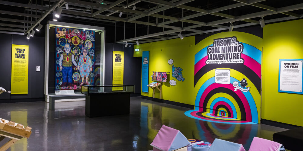 the exhibition with the tapestry in the background and in the foreground building cushioned blocks to create an artwork