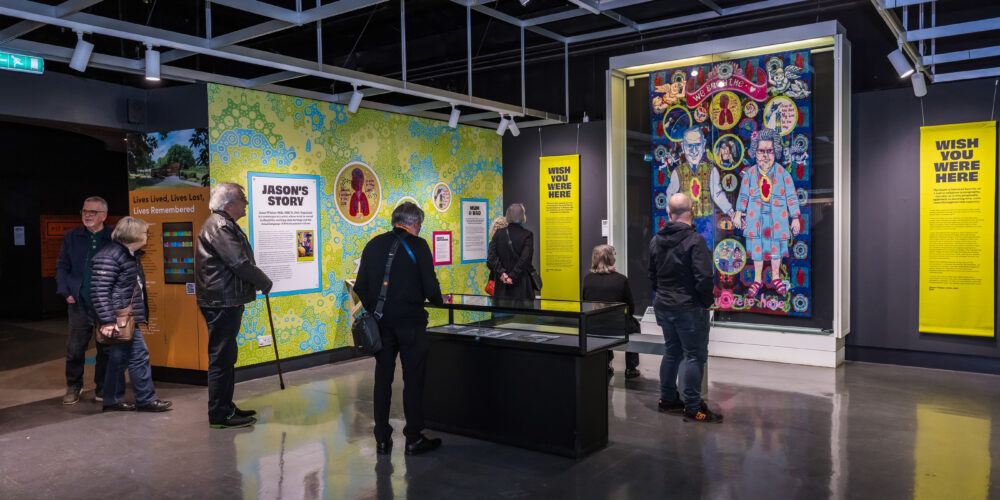 people stood in the exhibition looking at the exhibition walls, bright green and blue in colour